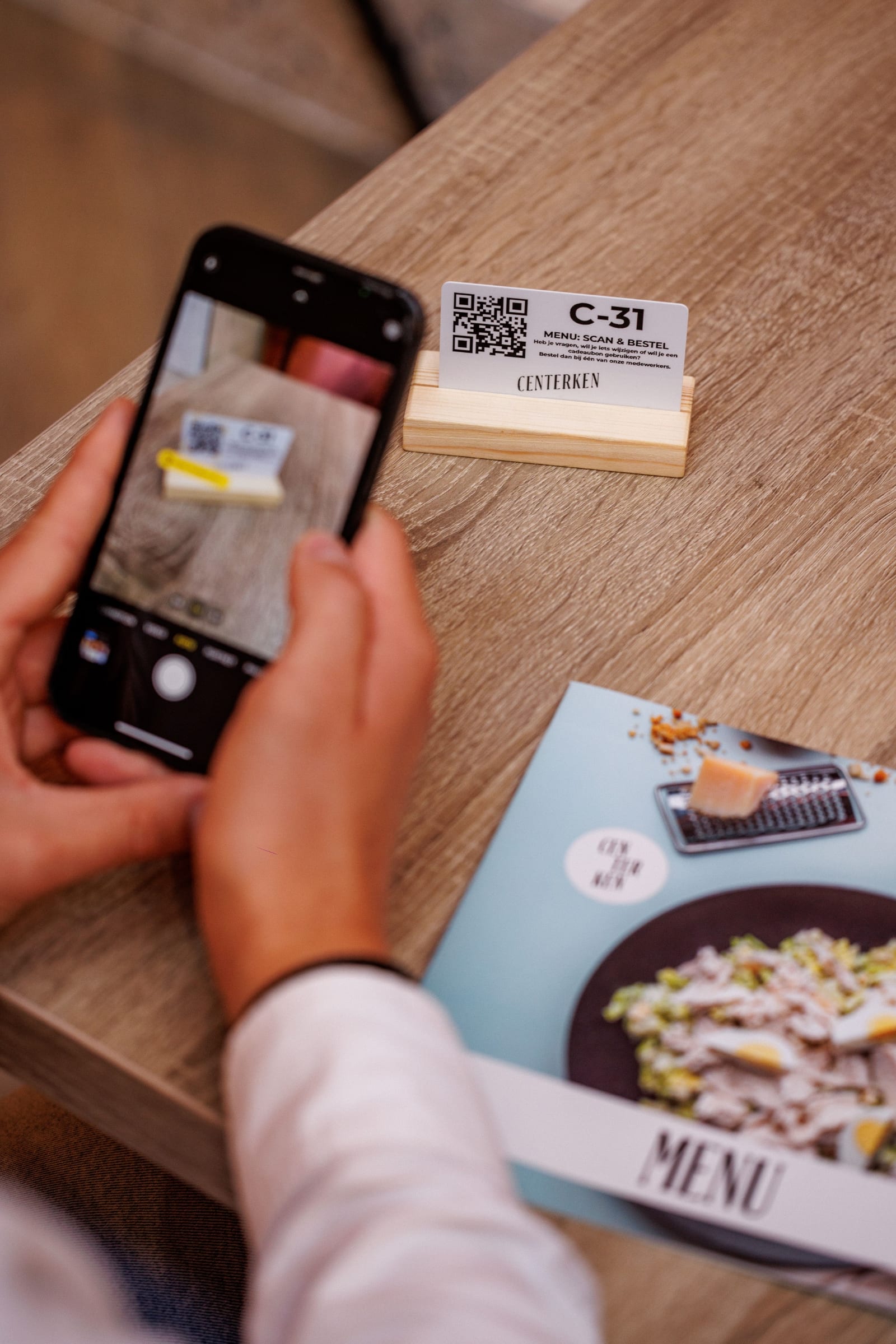 Smartphone scant de QR-code op een tafelkaartje C-31 van Centerken