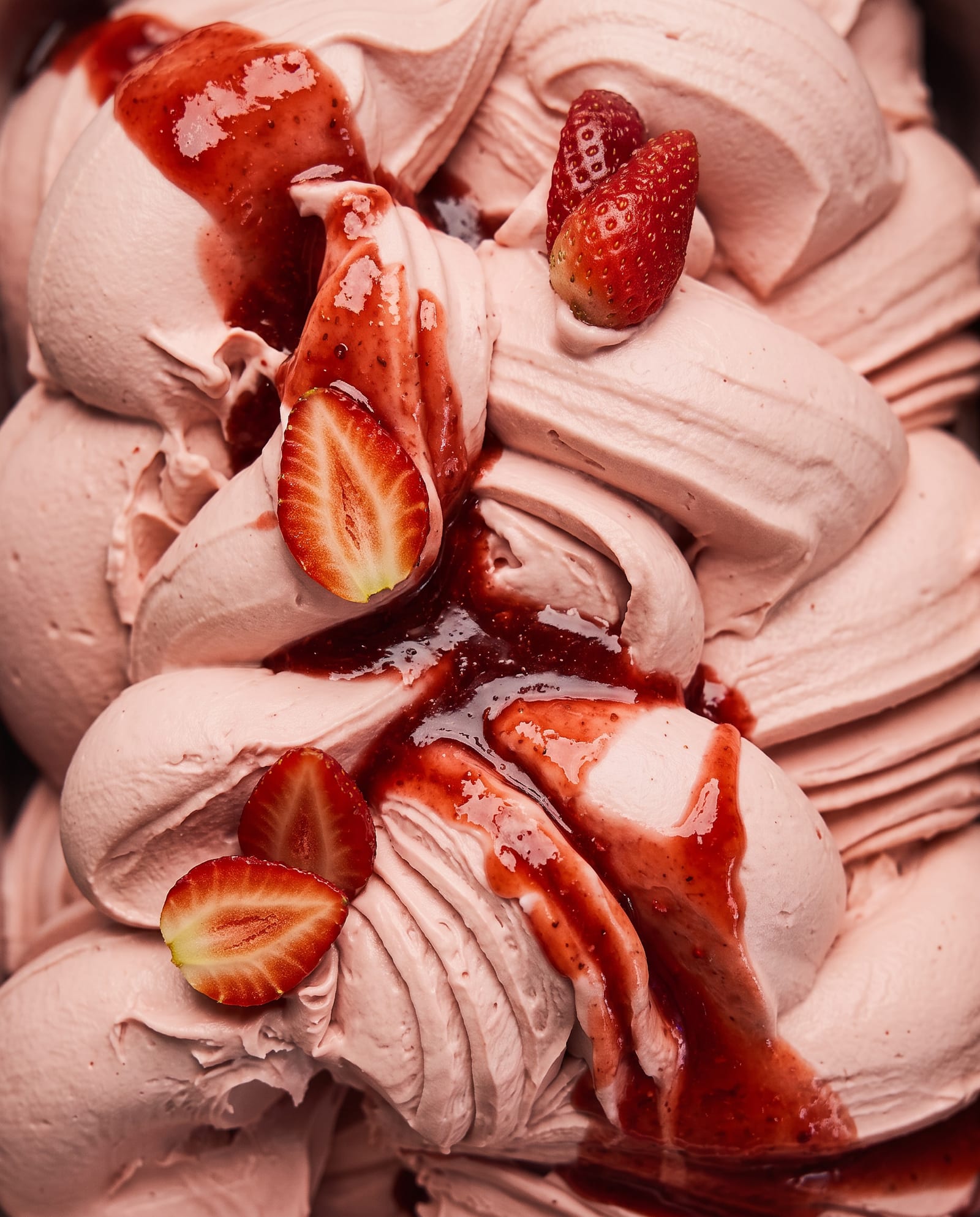 Close-up: roze aardbeienijs met halve verse aardbeien en aardbeiensaus