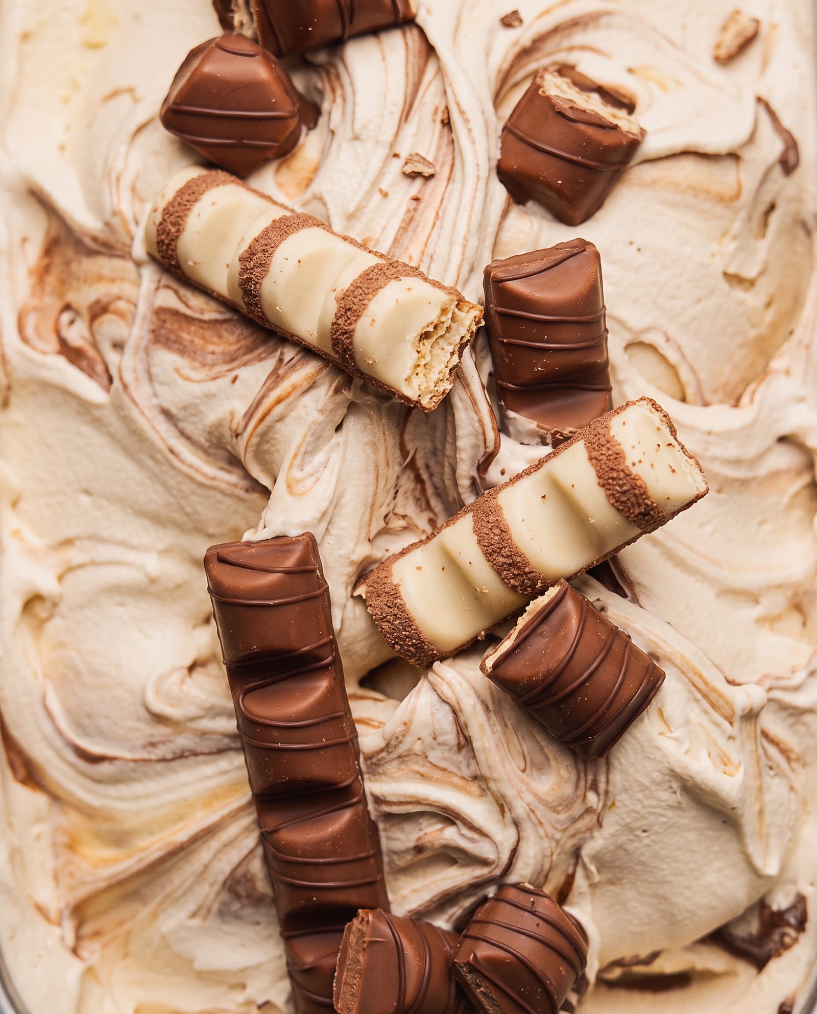 Close-up: crèmekleurig ijs met een chocolade-hazelnootswirl en stukken Kinder Bueno