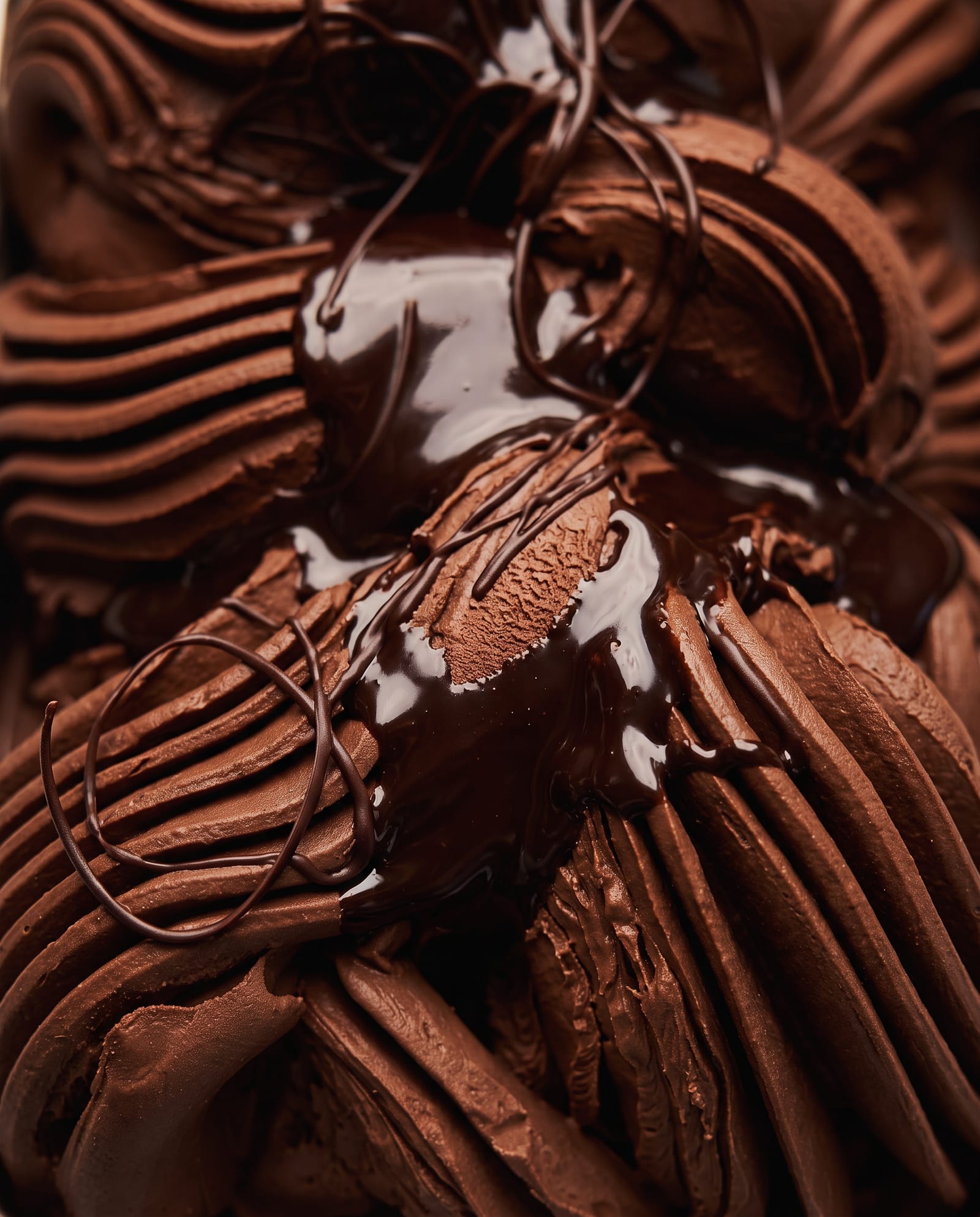 Close-up: donker fondant-chocolade-ijs in diepe ribbels met glanzende pure chocoladesaus