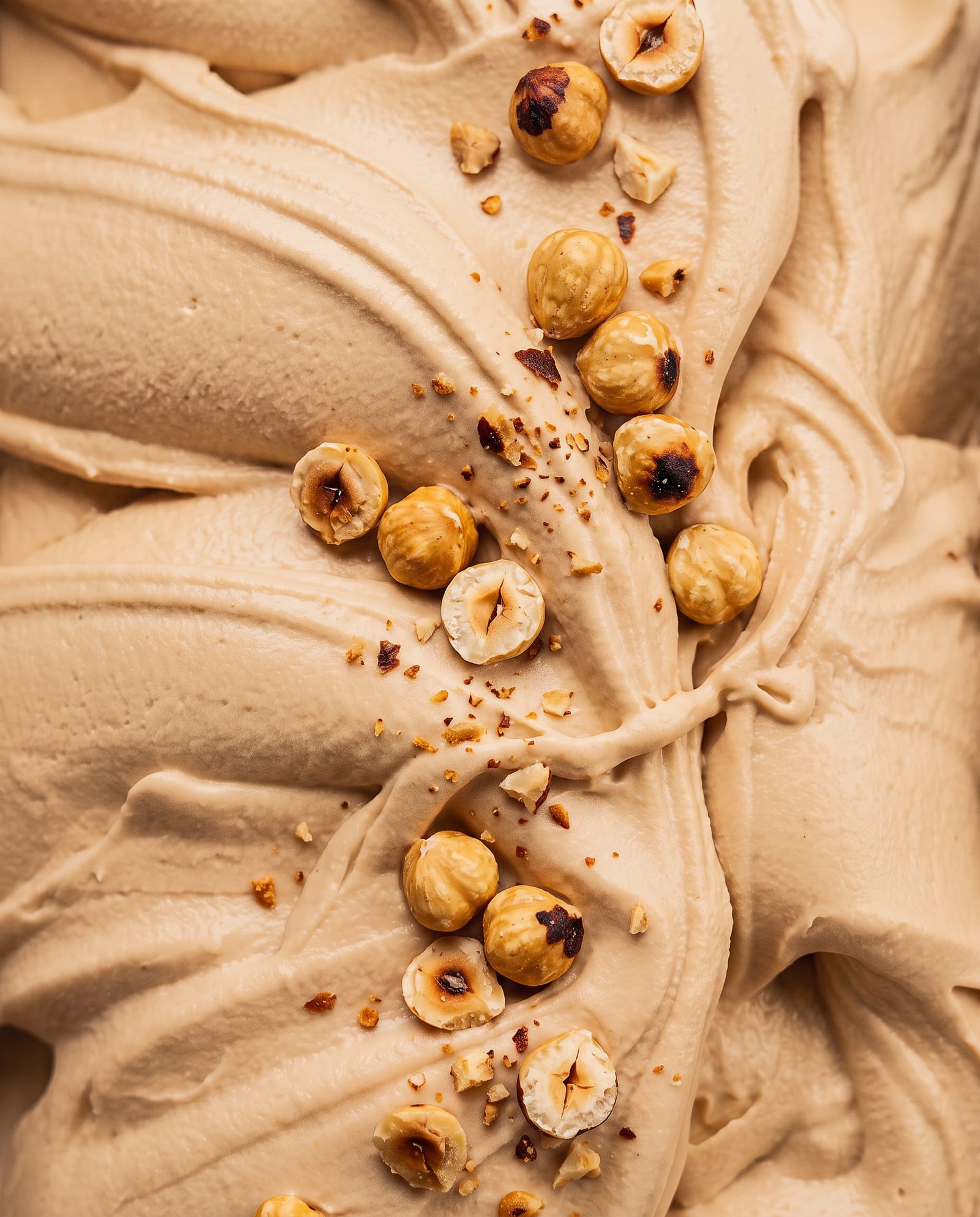 Close-up: koffie-caramelkleurig pralinéijs met hele en gehakte hazelnoten