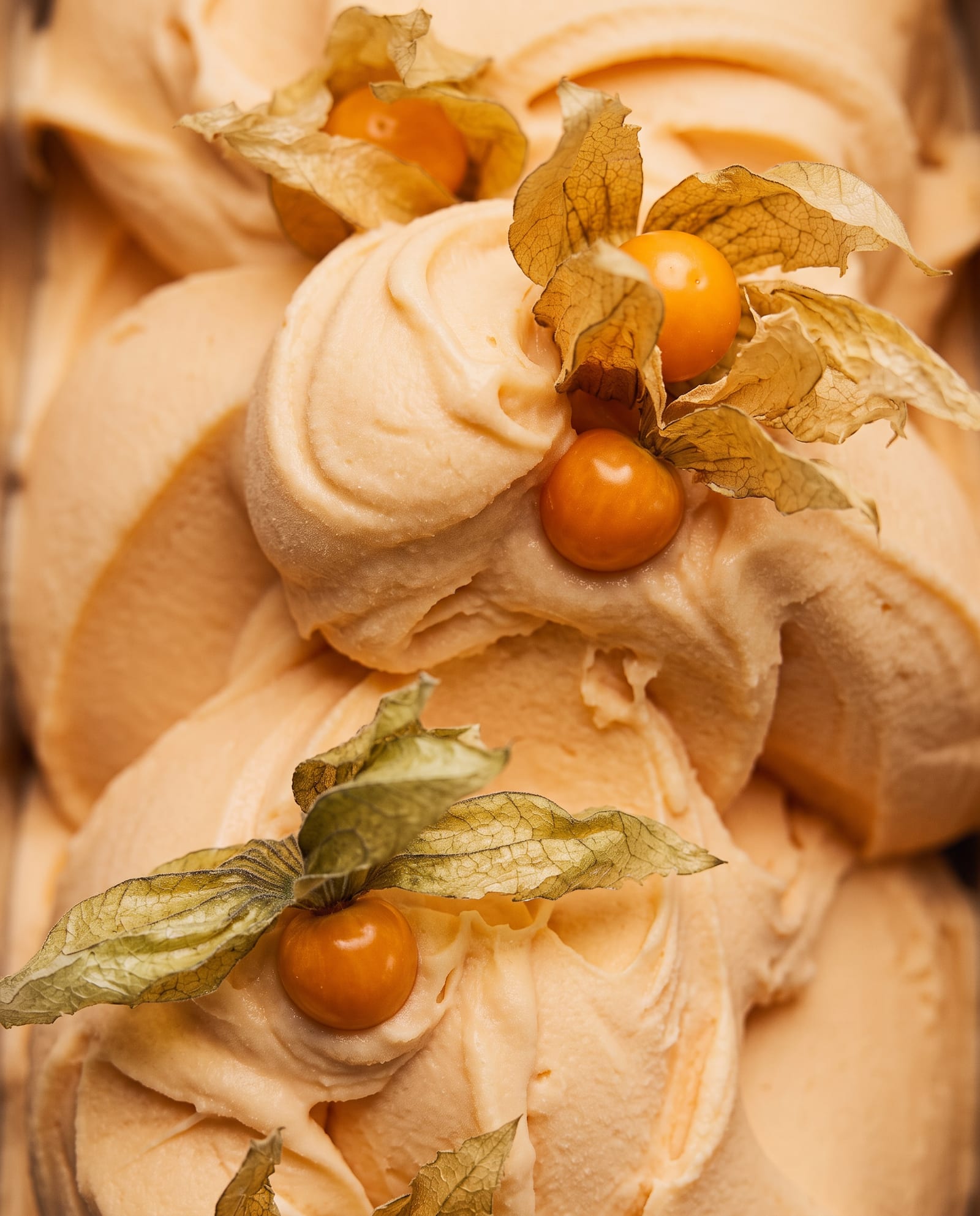 Close-up: abrikooskleurige tropical sorbet in swirls met physalis (goudbessen)